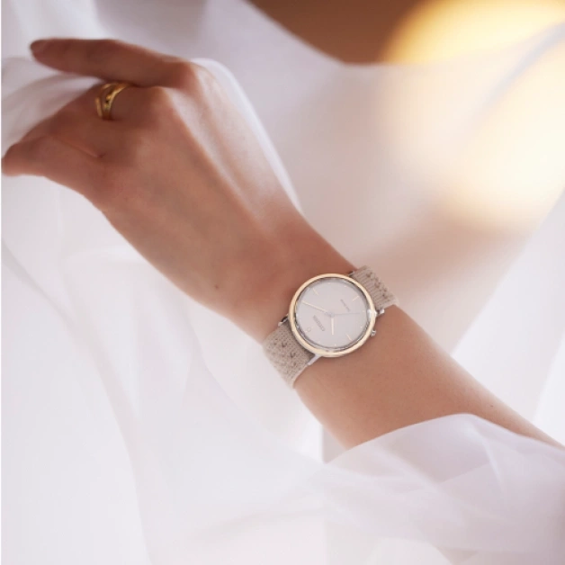 Wrist watch with a beige strap on a woman's wrist, close-up shot.