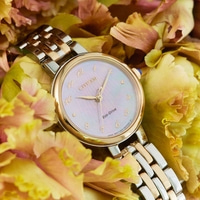 Citizen watch with gold and silver band, surrounded by yellow flowers.