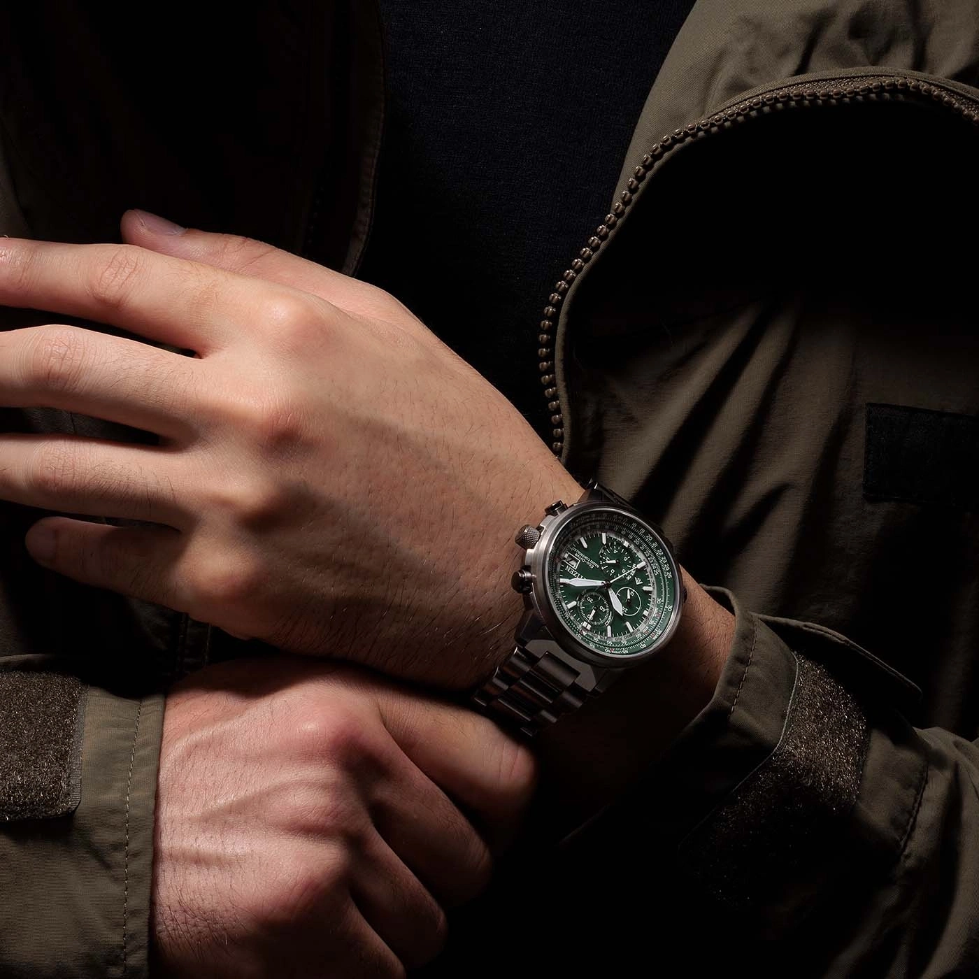 Man wearing a green watch, hands crossed, dark jacket, close-up shot