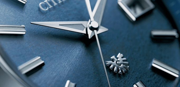 Close-up of a blue watch face with silver hands and markers, Citizen logo.