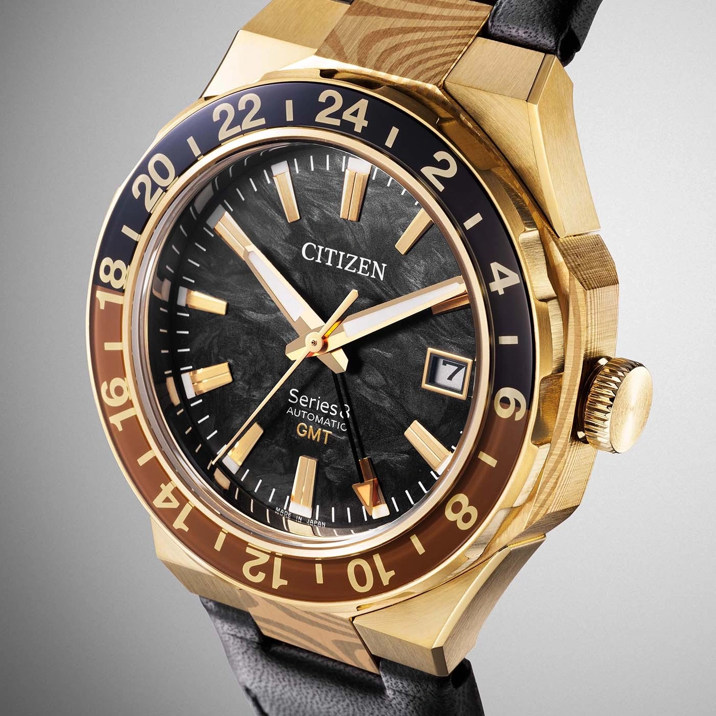 A close-up shot of a luxurious gold Citizen GMT watch with a black dial and brown accents on the bezel.