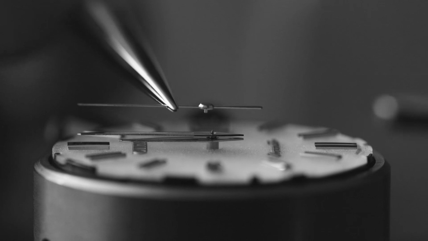 Close-up of watch mechanism being assembled with precision tools.