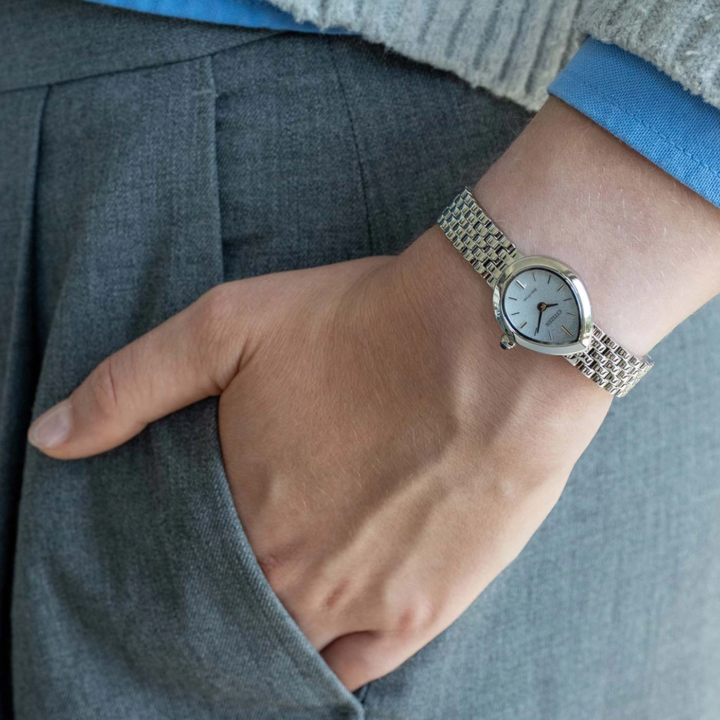 Person wearing a silver watch on their left wrist, with hand in pocket.