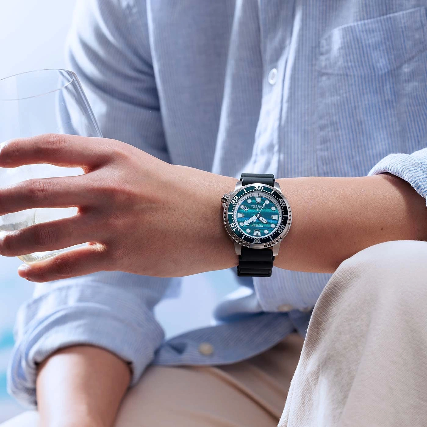 A man's wrist wears a blue Citizen watch with a black strap.