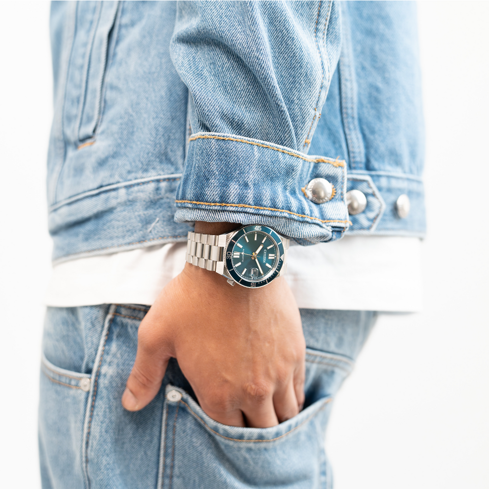 Man wearing a denim jacket and jeans with a watch.