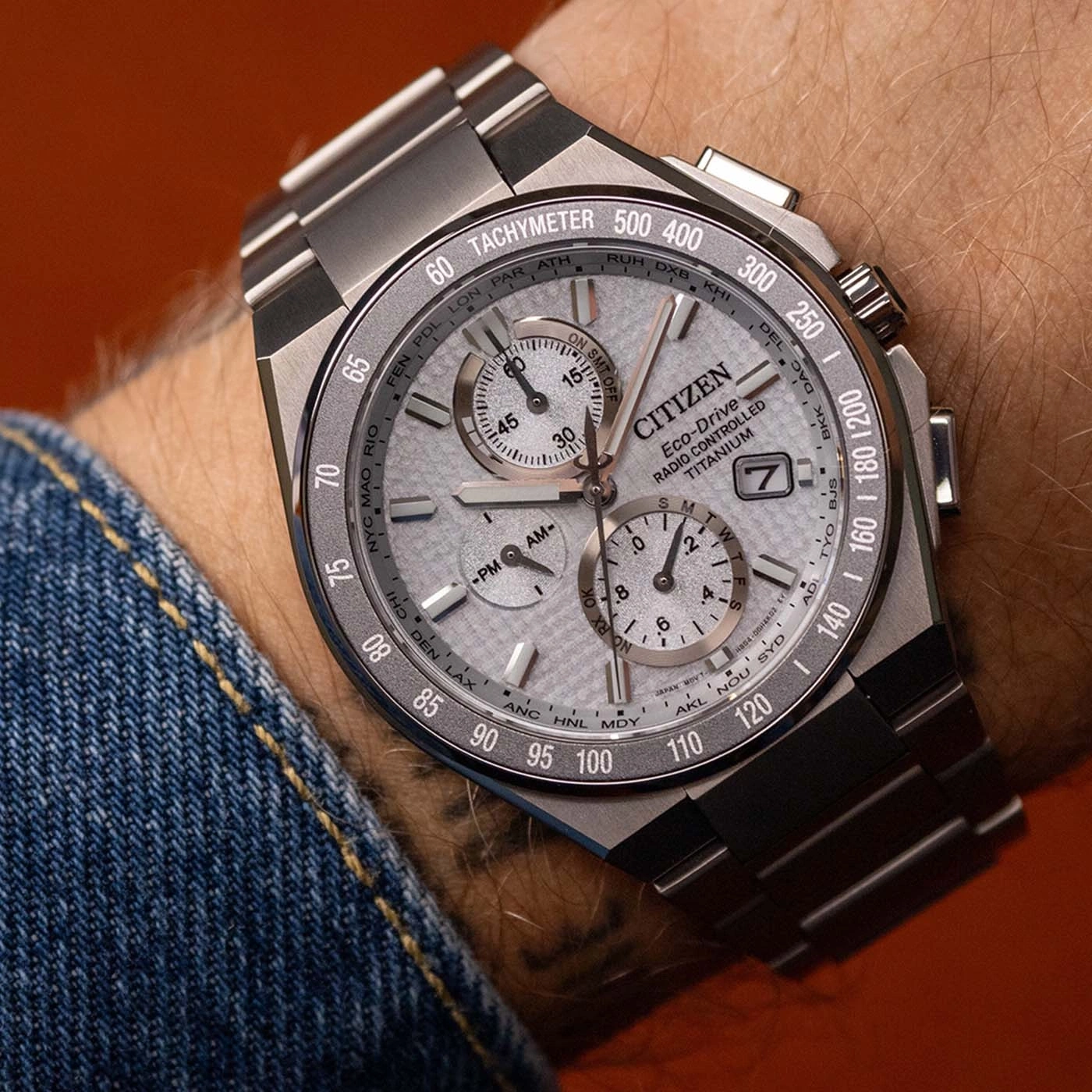 Close-up of a Citizen Eco-Drive Titanium watch on a wrist, featuring a tachymeter and world cities.