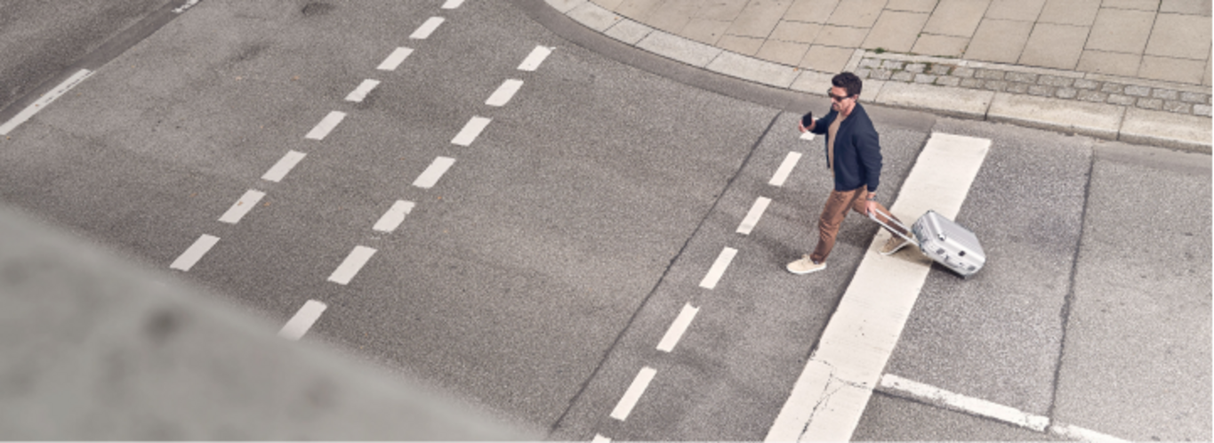 Man with suitcase crossing the street at a crosswalk