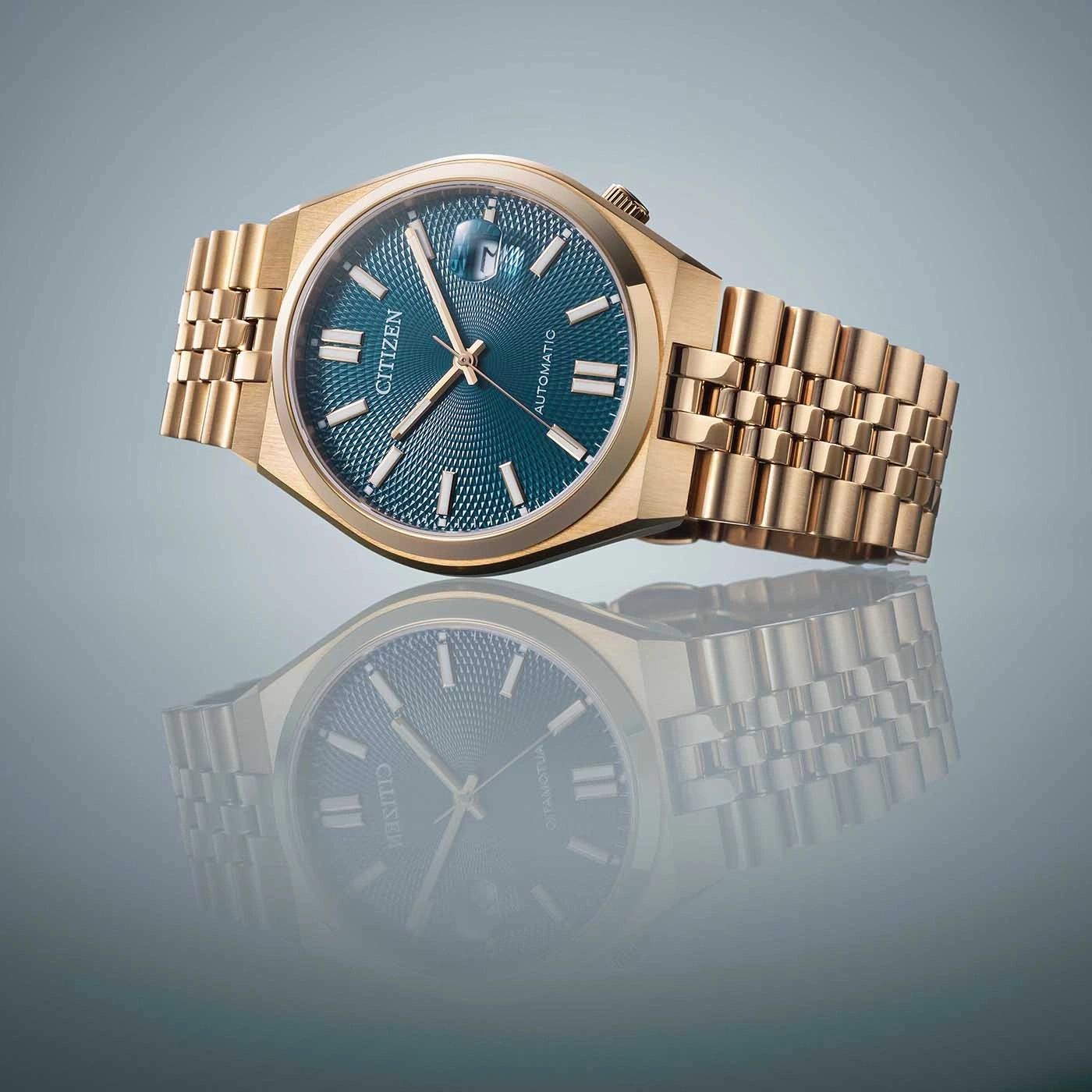 Gold Citizen watch with blue face and reflection on a surface.