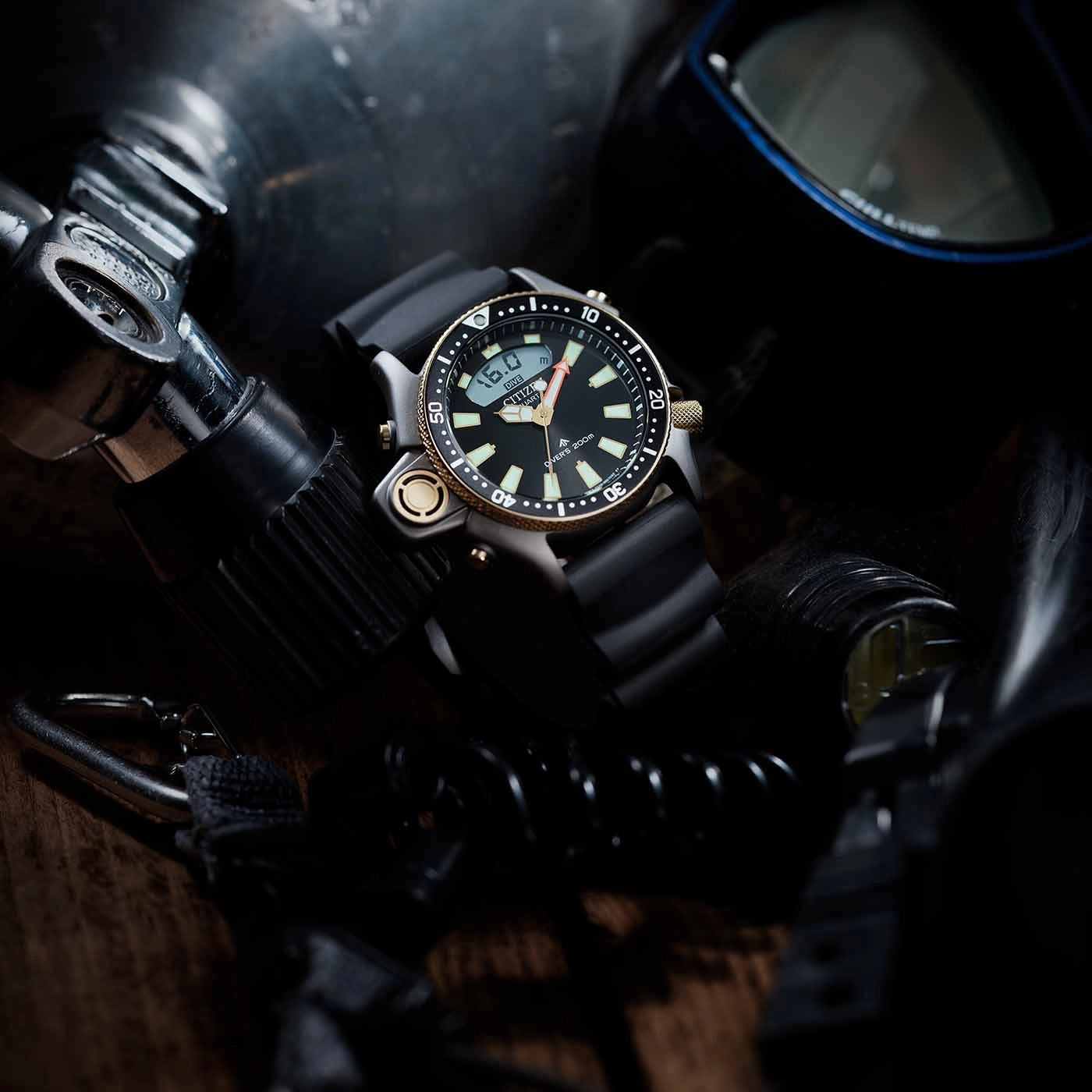 Close-up of a diving watch with diving equipment in the background.