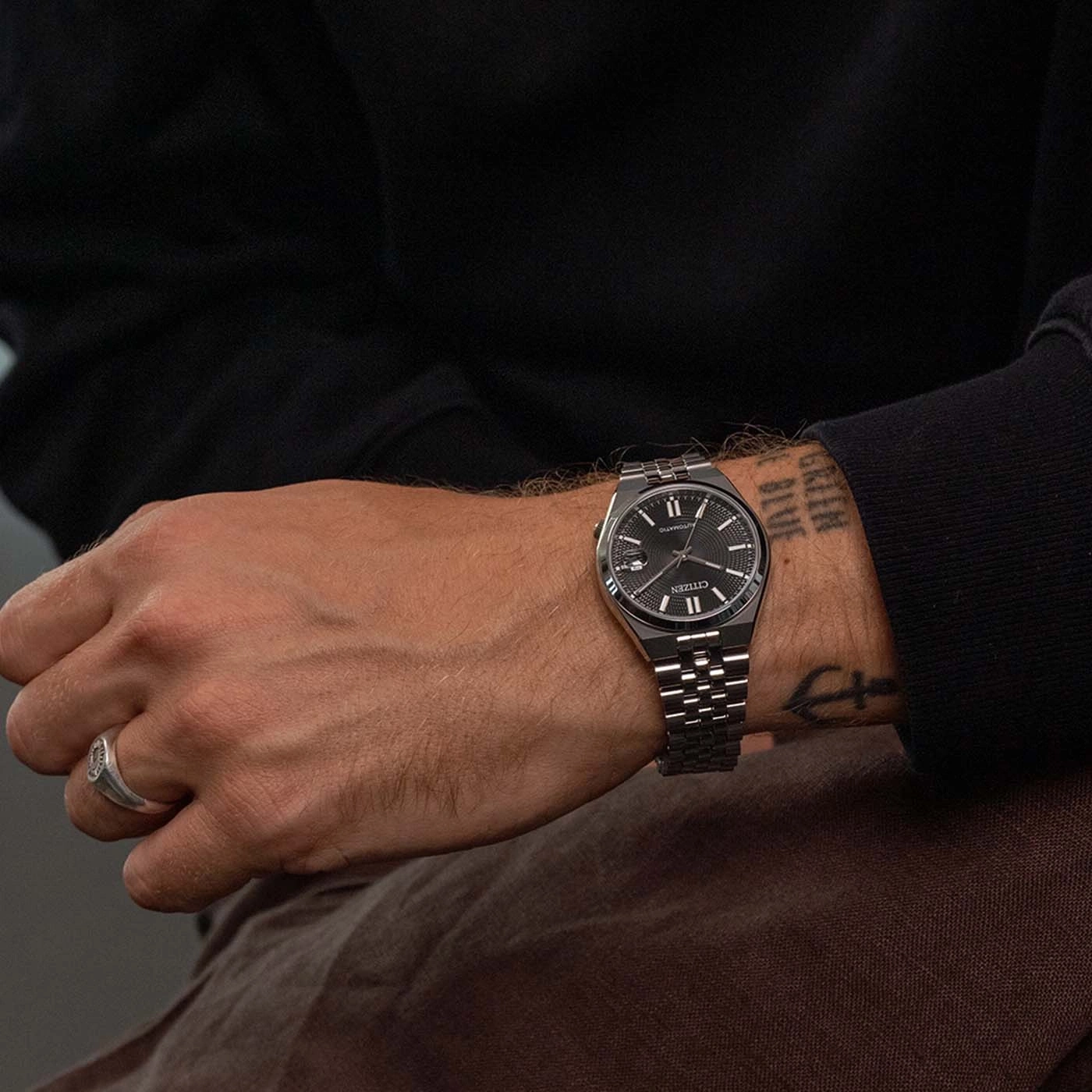 Man wearing a black Citizen automatic watch with silver band and ring.