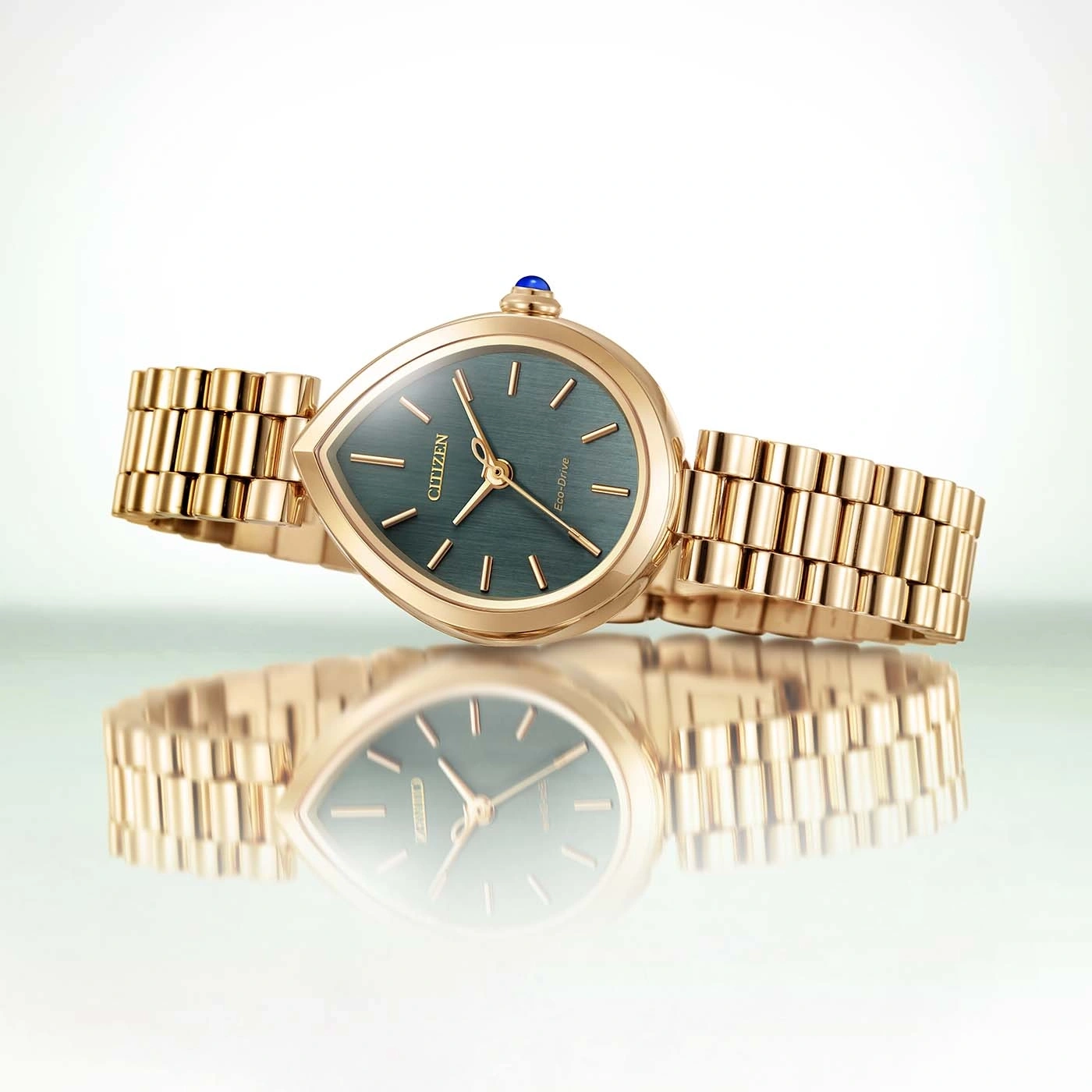A gold Citizen Eco-Drive watch with a teardrop face and green dial.