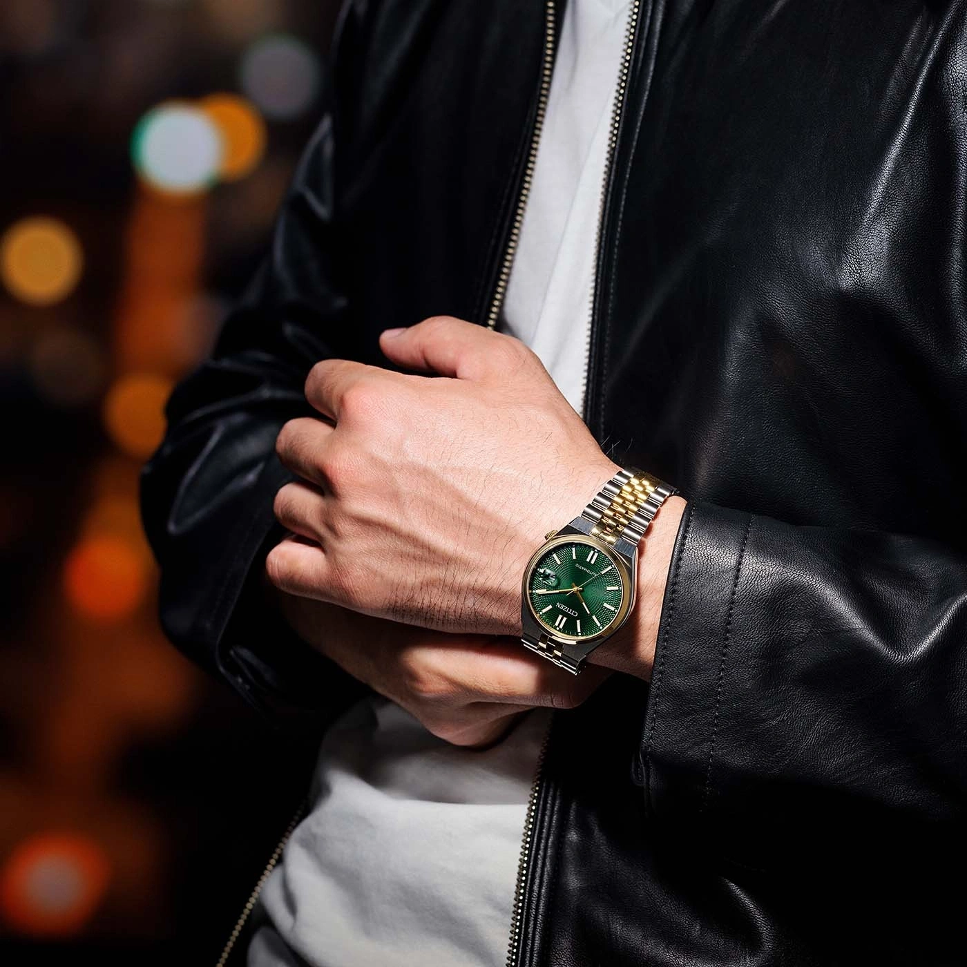 Man wearing a watch with a green face and gold and silver band