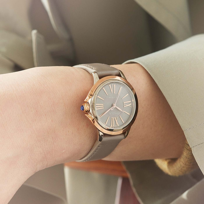 Close-up of a Citizen watch on a wrist, with a grey strap and rose gold accents.