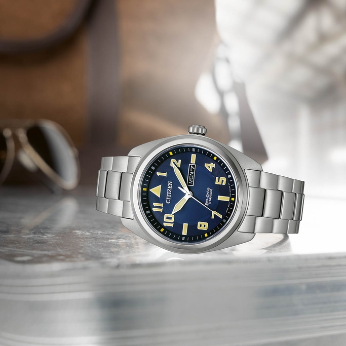 Citizen watch with blue face and silver band on a reflective surface