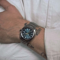 A man's wrist with a Citizen Eco-Drive watch and tattoos.