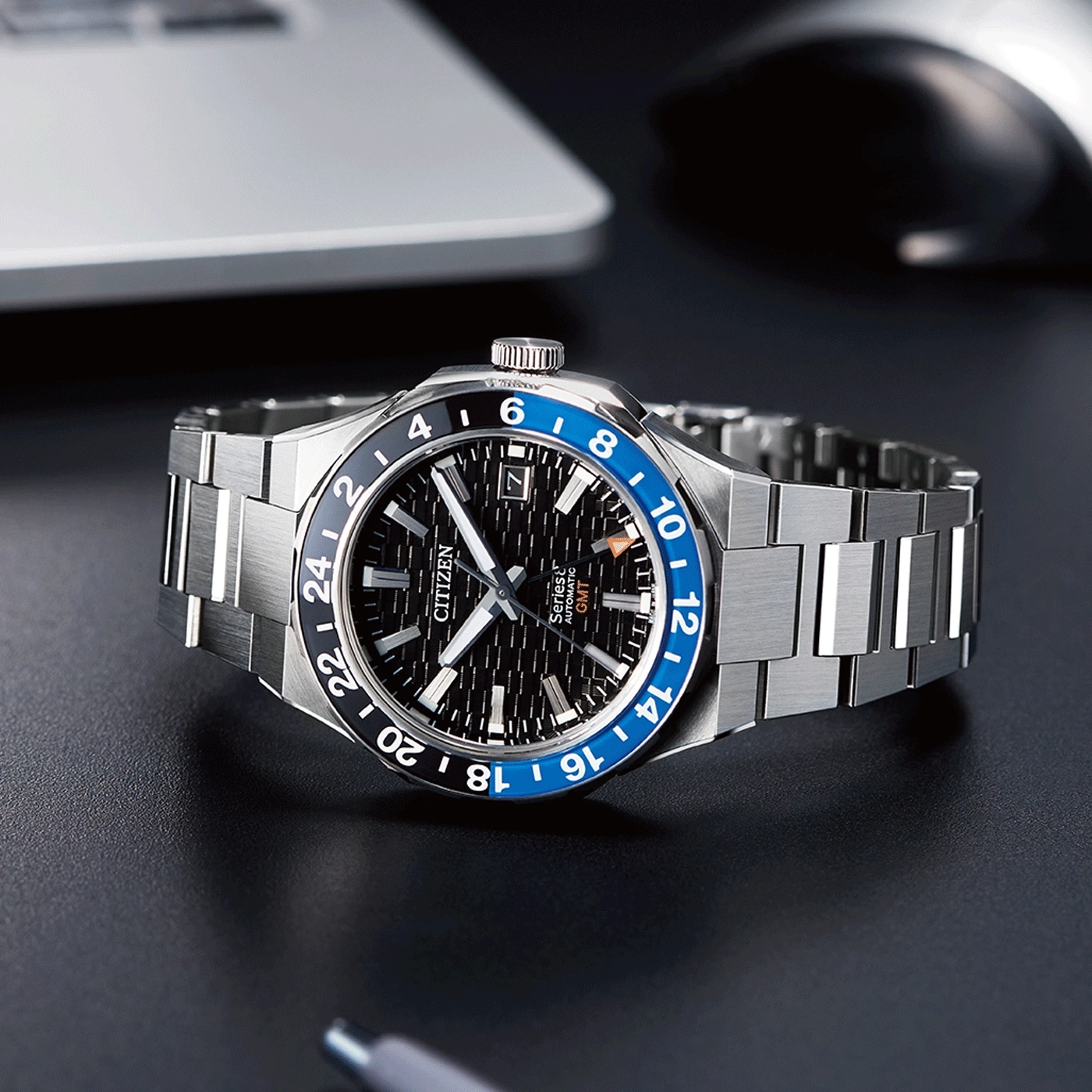 Citizen watch with black and blue bezel, stainless steel bracelet, and GMT function.