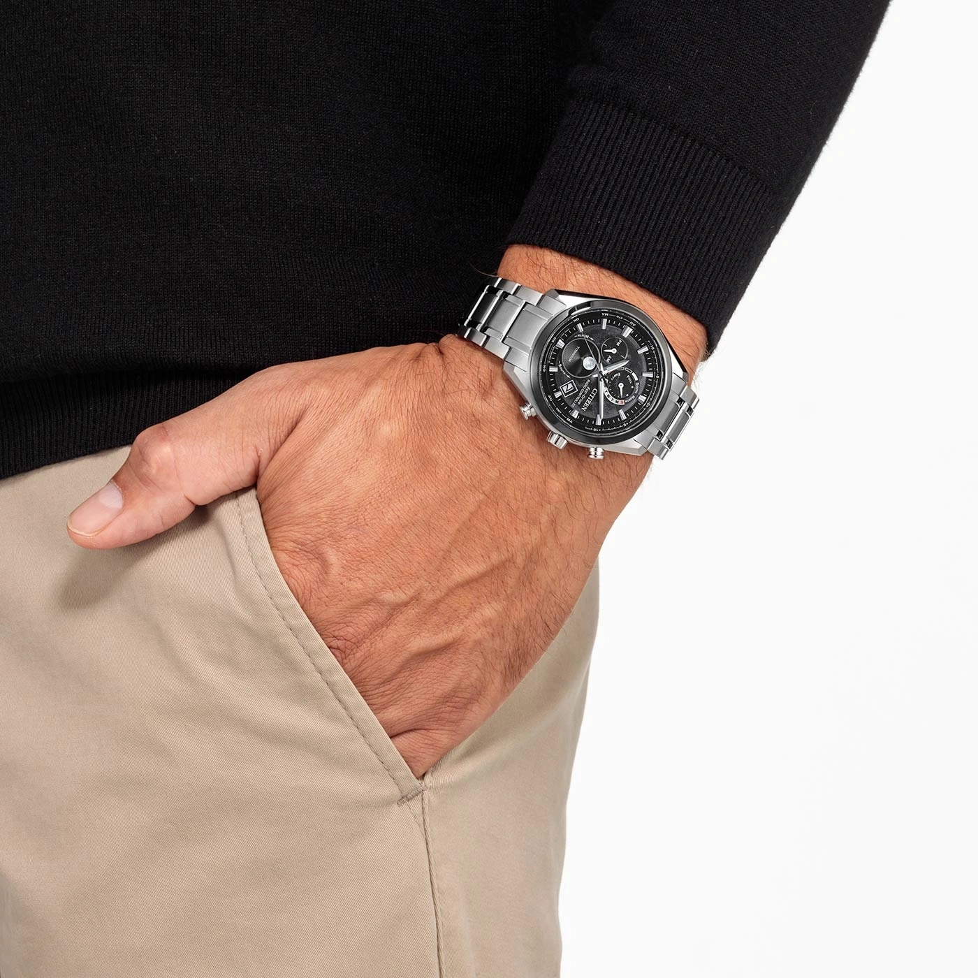 Man wearing a watch, hand in pocket, black sweater, beige pants
