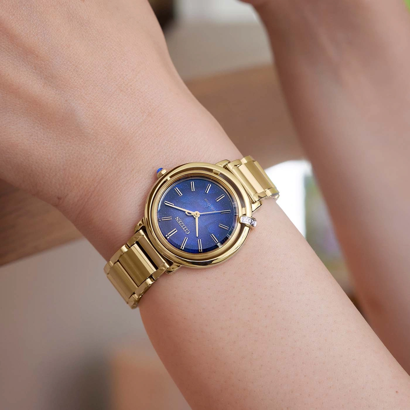 Gold watch on wrist with blue face, Citizen brand, close-up shot