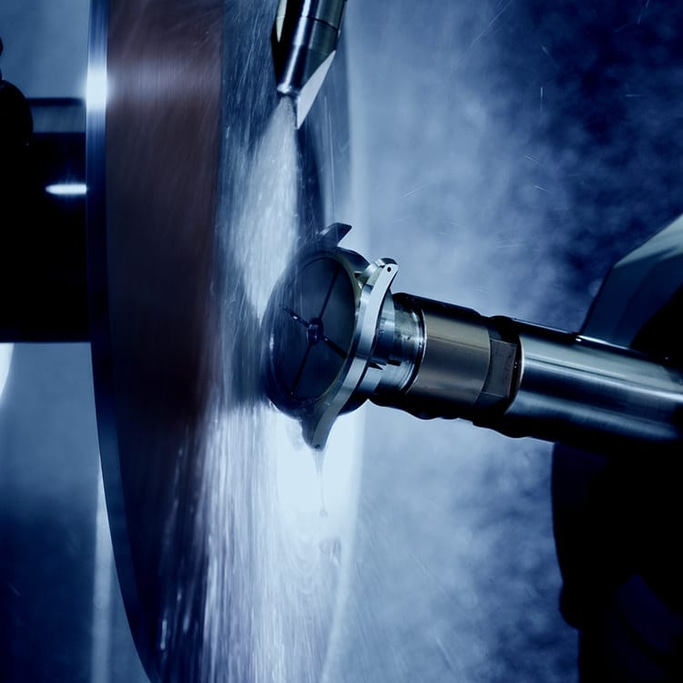 Metalworking process with a rotating tool and water spray, close-up shot.