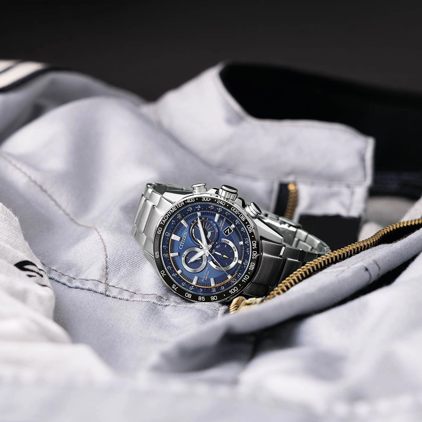 Citizen watch on a grey jacket with a blue face and silver band.