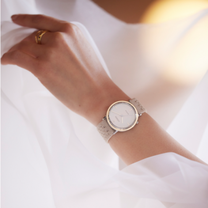 Wrist watch with a beige strap on a woman's wrist, close-up shot.