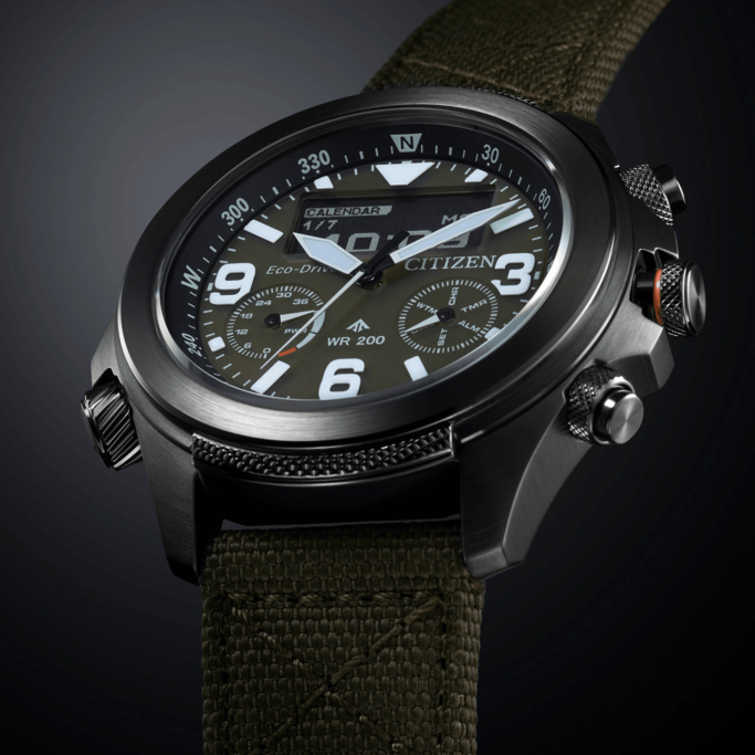 Citizen watch with digital display, olive green strap, and black casing, showing time and date.