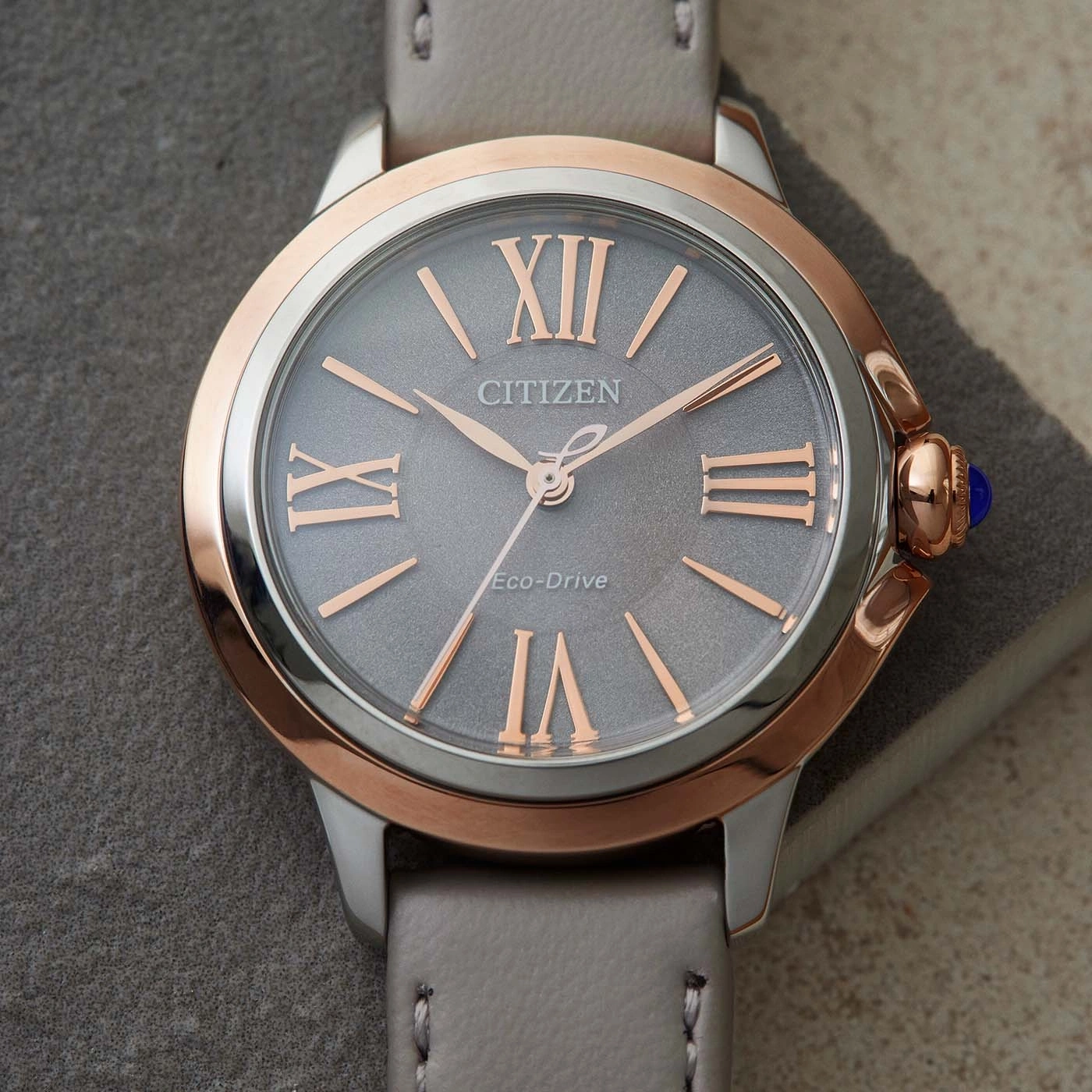Citizen watch with grey face, rose gold accents, and grey leather strap.