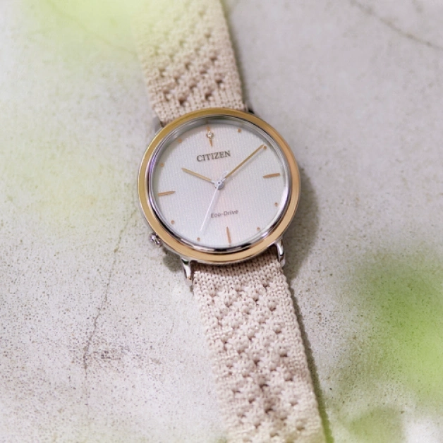 Citizen watch with a cream-colored band on a textured surface