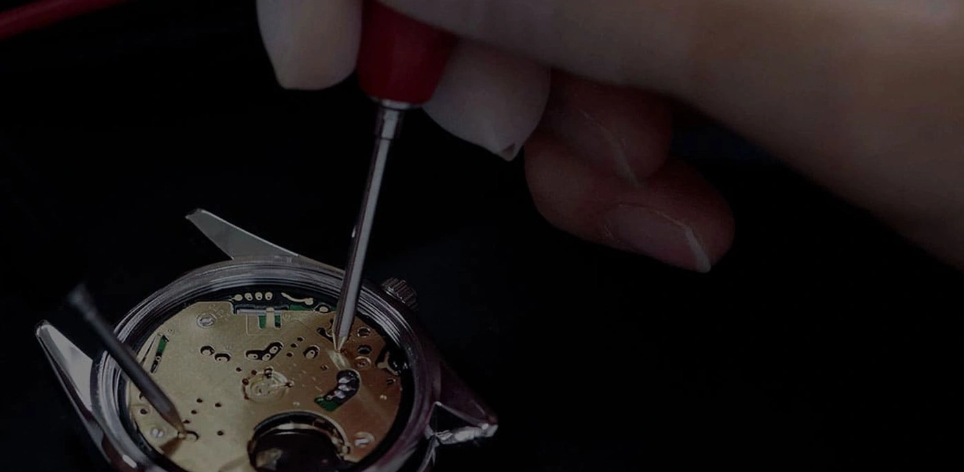 Watch repair with tools and hands, close-up shot, black background