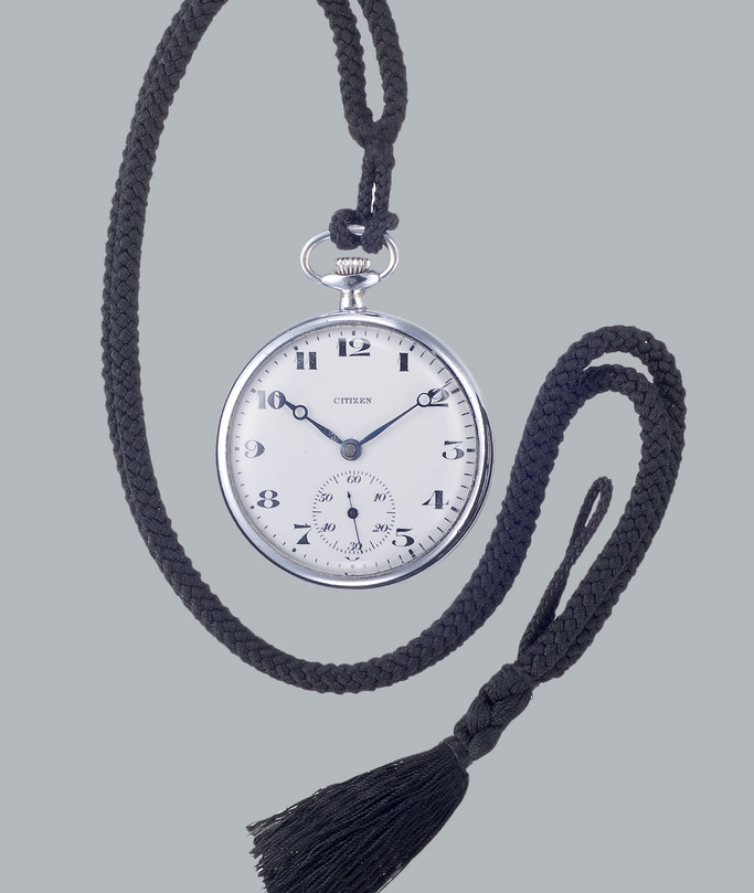 Taschenuhr mit schwarzem Band und Quaste, Marke Citizen, silbernes Gehäuse, weißes Zifferblatt.