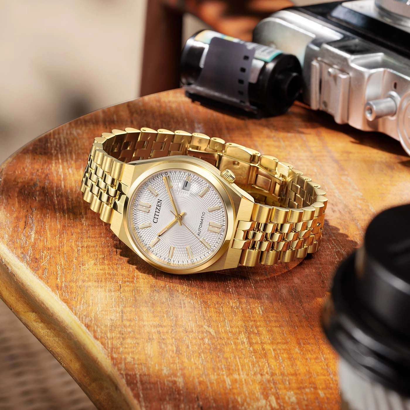 Gold Citizen watch with automatic movement on wooden surface.
