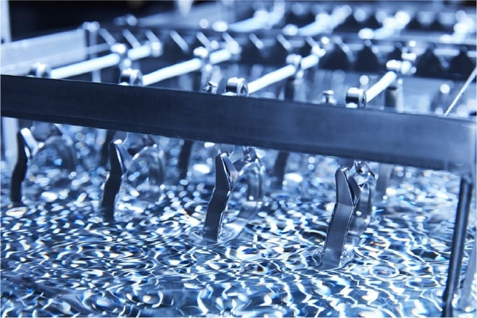 Metal parts being dipped in a liquid, industrial process, close-up shot.