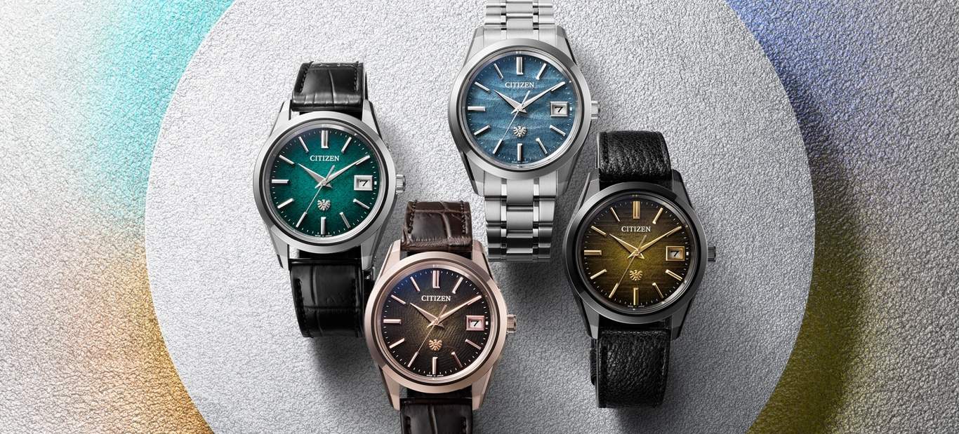 Four Citizen watches with different colored faces and straps on a textured background.