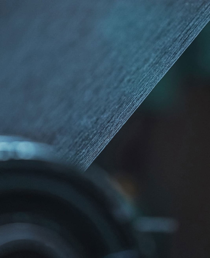 Close-up of textured paper with a dark, blurred background and soft lighting.