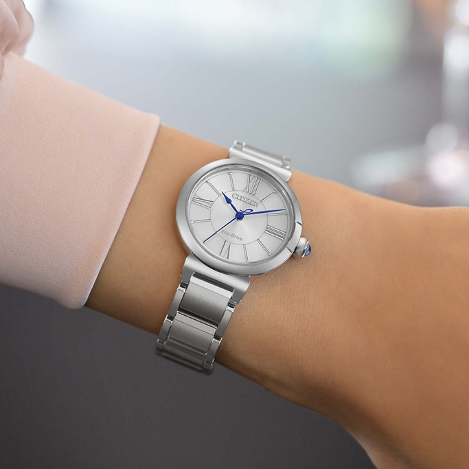 A woman wears a silver Citizen Eco-Drive watch with a Roman numeral dial.
