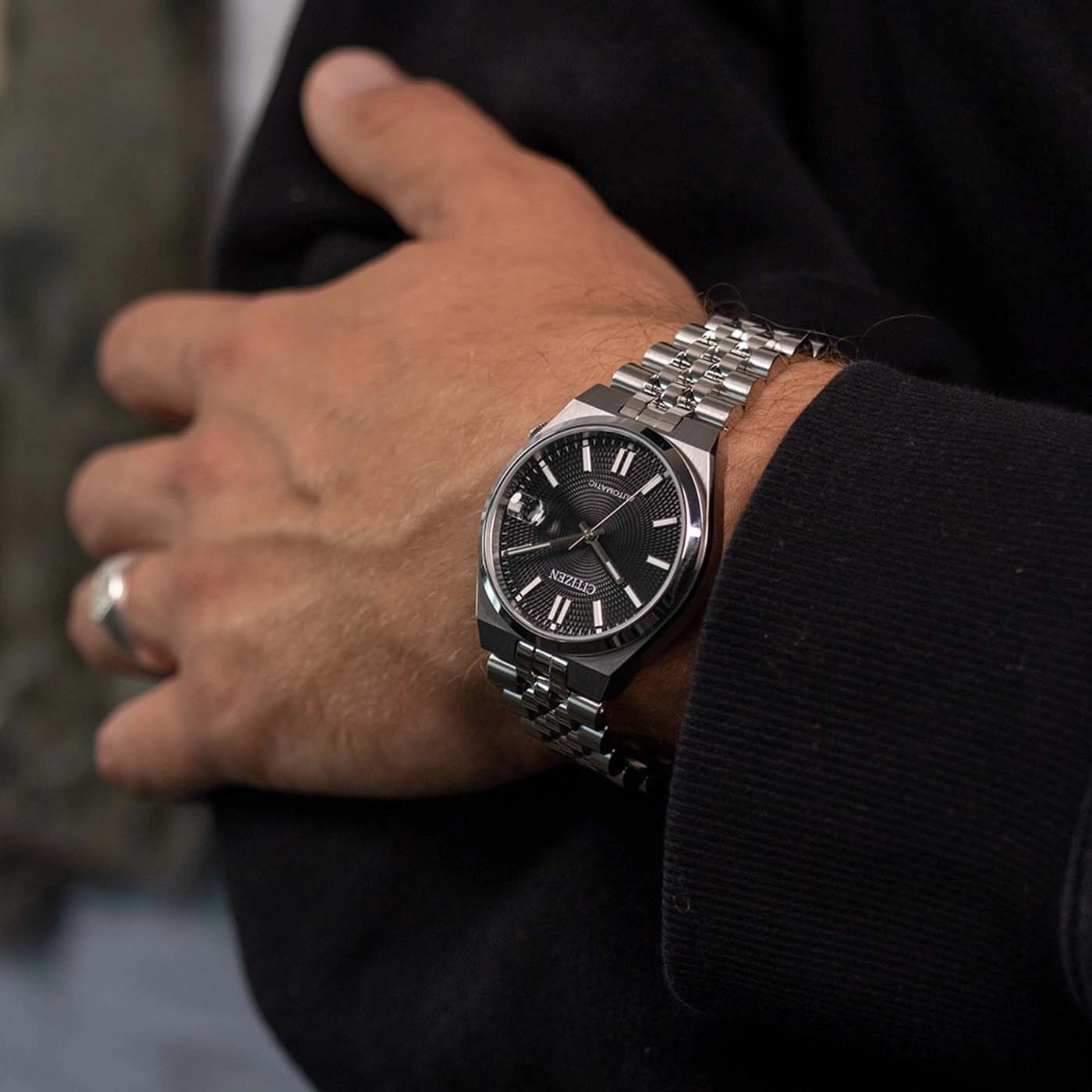A man wearing a Citizen automatic watch on his left wrist.