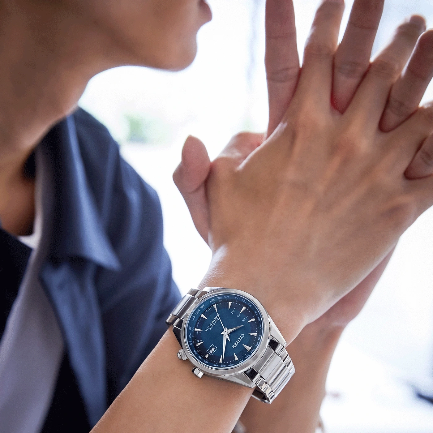 Person wearing a Citizen watch with a blue face and silver band.