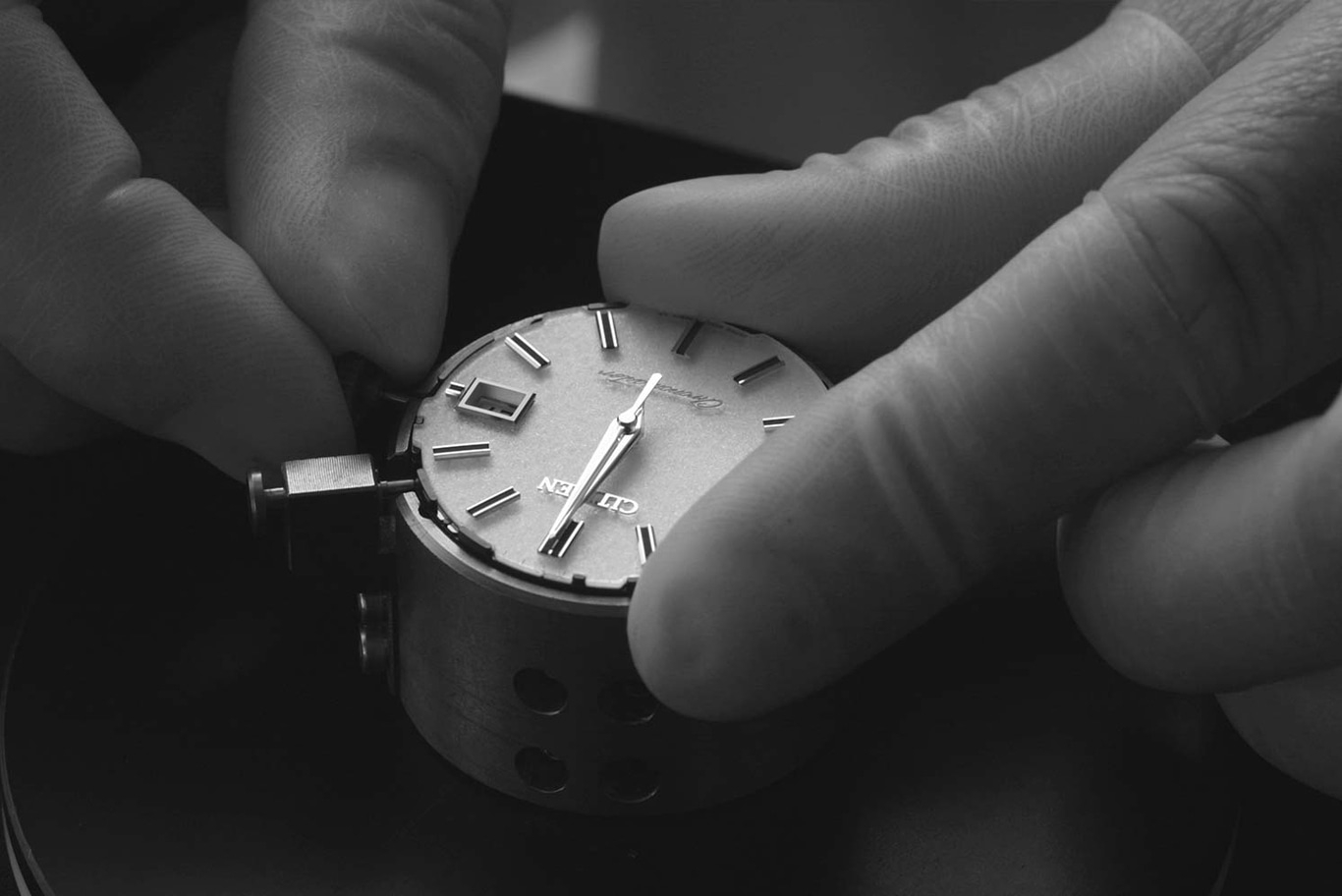 Hände montieren eine Uhr. Nahaufnahme von Zifferblatt und Zeigern.