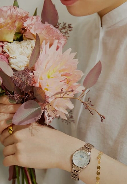 Woman holding flowers, wearing a watch and bracelet, close-up shot