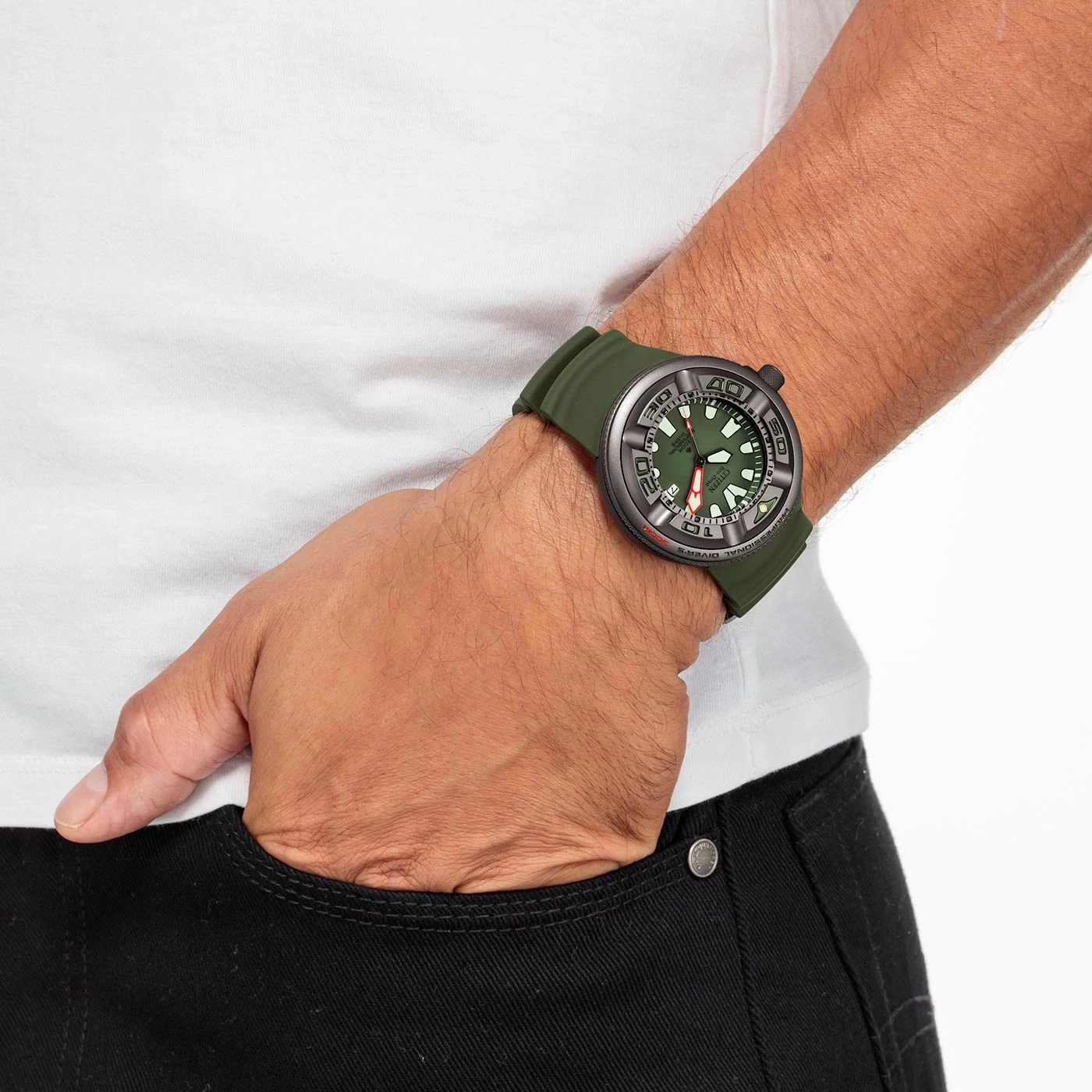 Man wearing a green watch, hand in pocket, white shirt, black pants.
