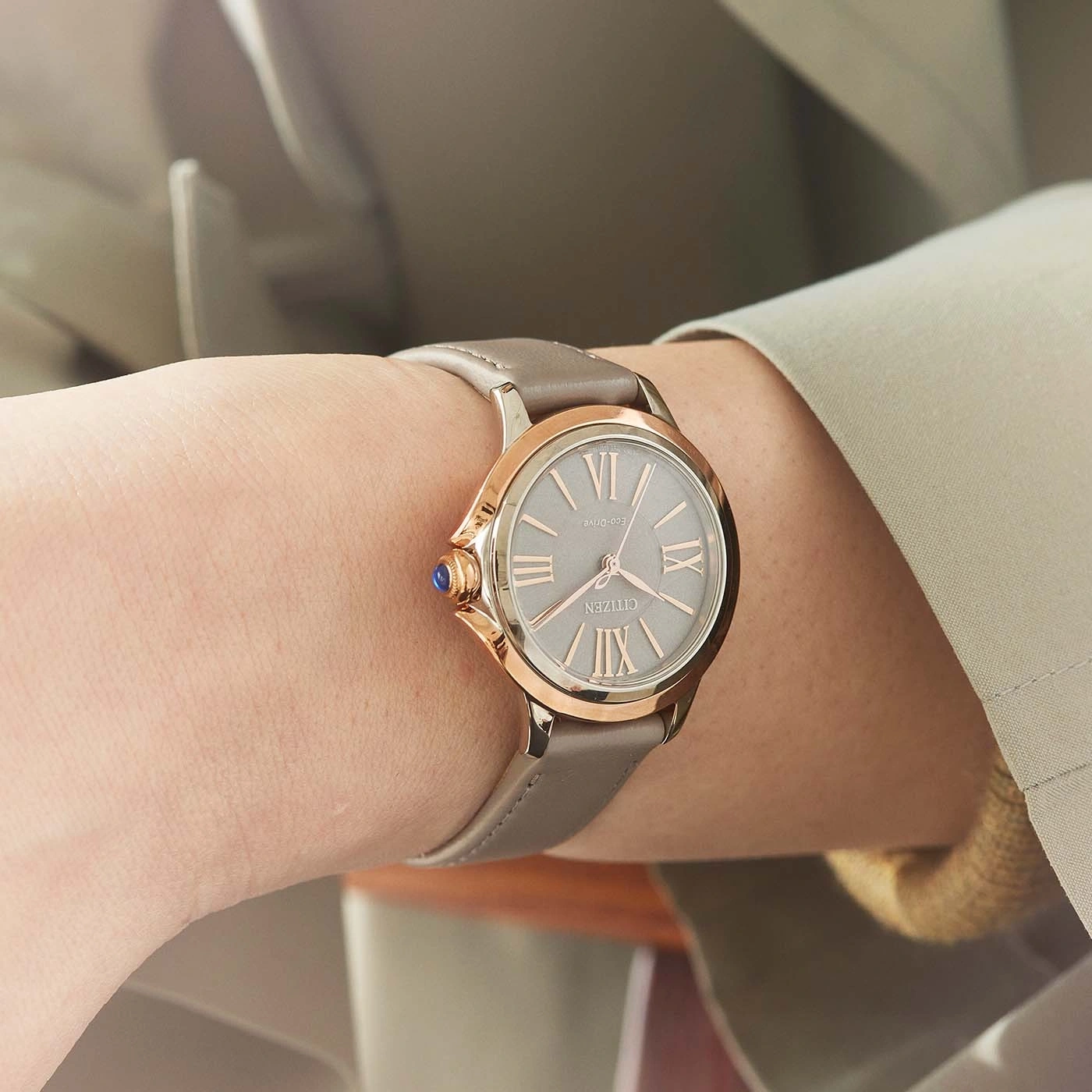 Close-up of a Citizen watch on a wrist, with a grey strap and rose gold accents.