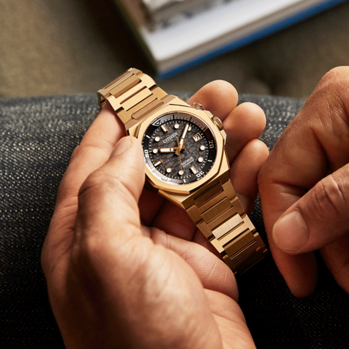 Close-up of a gold Citizen watch held by a person's hands.