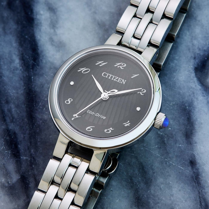 Citizen watch with a dark face and silver band on a marble surface.