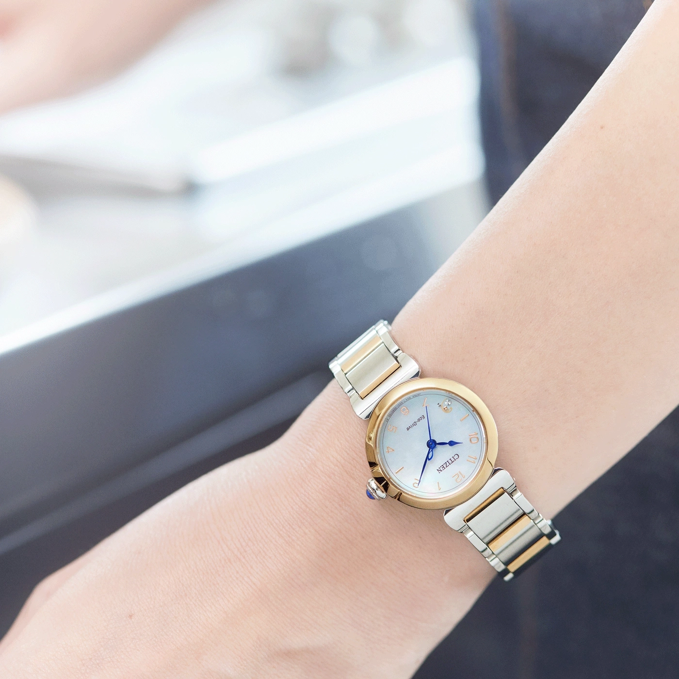 A woman's wrist with a Citizen Eco-Drive watch, gold and silver.