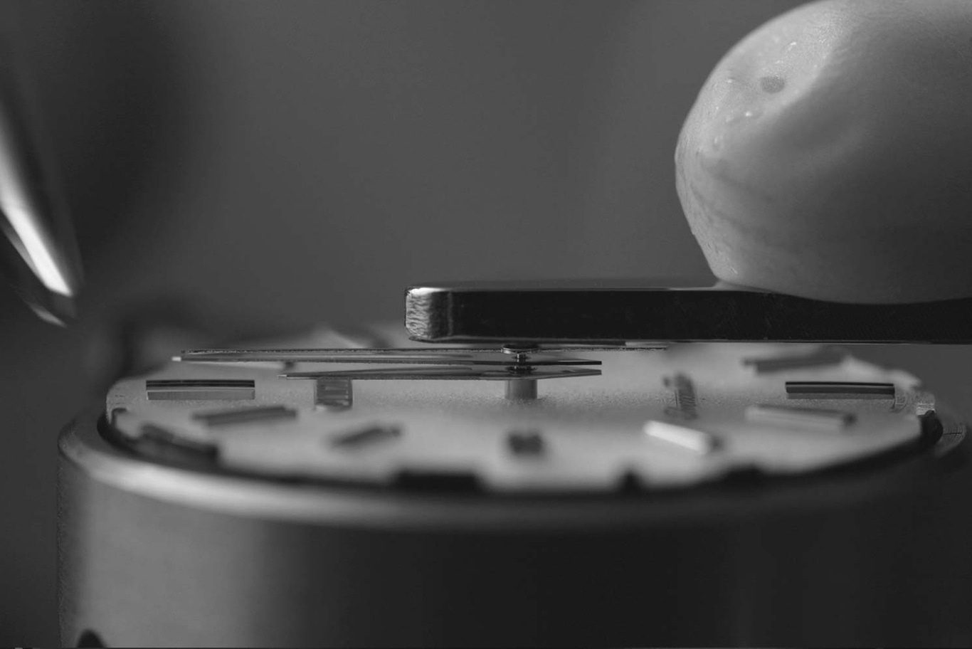 Close-up of watch mechanism being assembled with tools and precision.