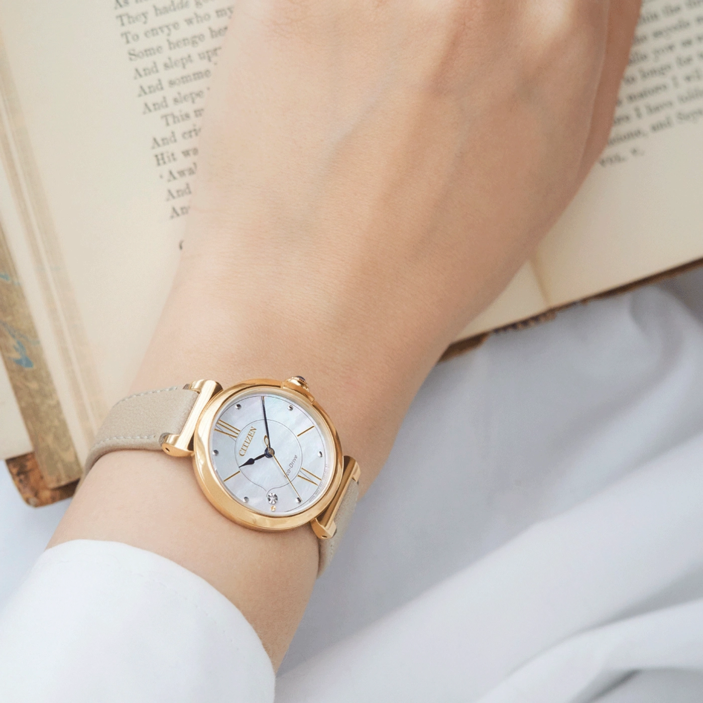Wristwatch on a wrist, gold watch with a light-colored strap, Citizen watch.