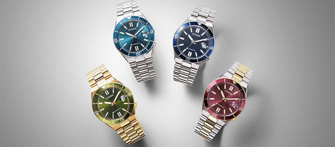 Four Citizen watches with different colored faces and metal bands.