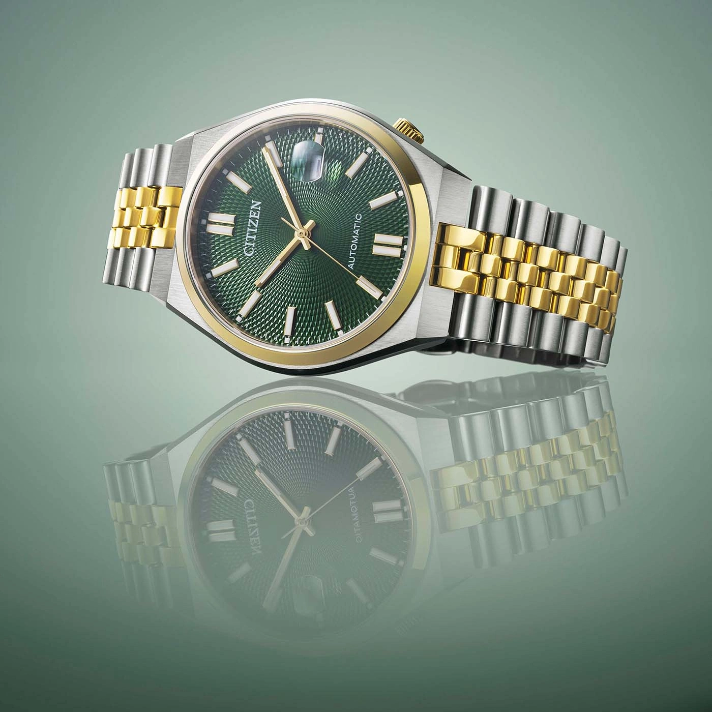 Citizen watch with green face and gold and silver band, reflected.