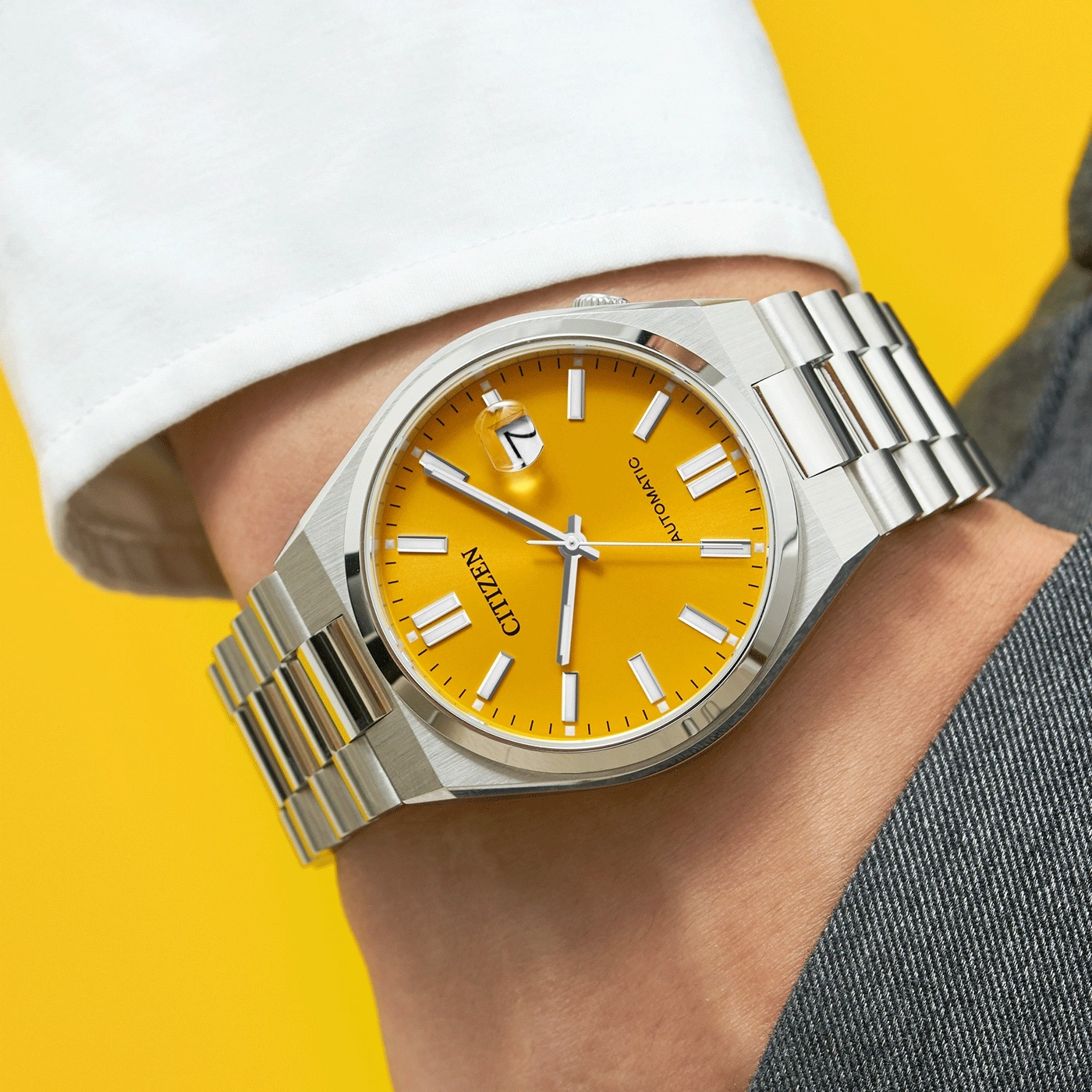 Citizen watch with yellow face and silver strap on wrist