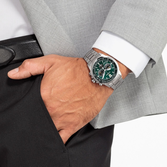 Man wearing a watch, suit, and holding his hand in his pocket.